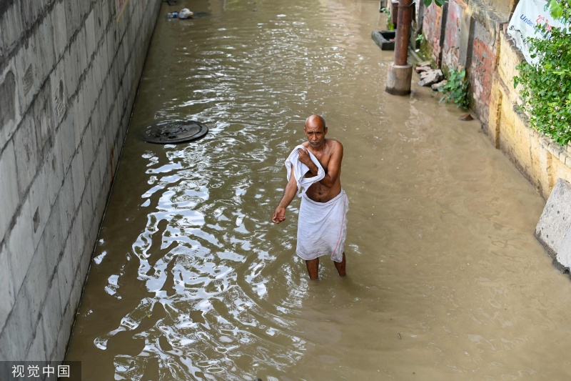 印度新德里因降雨街道被淹 民众涉水过街
