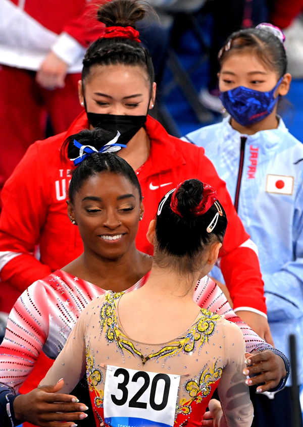 东京奥运会体操赛场，女子平衡木冠军管辰晨（背影者）接受对手们的祝贺。王霞光/摄 受访者供图