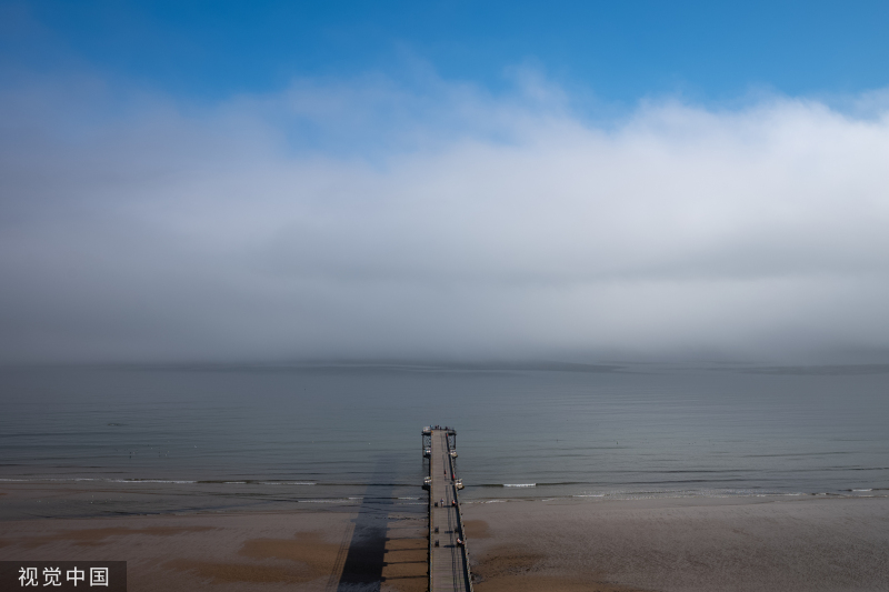 高温持续 浓雾笼罩英国海滩